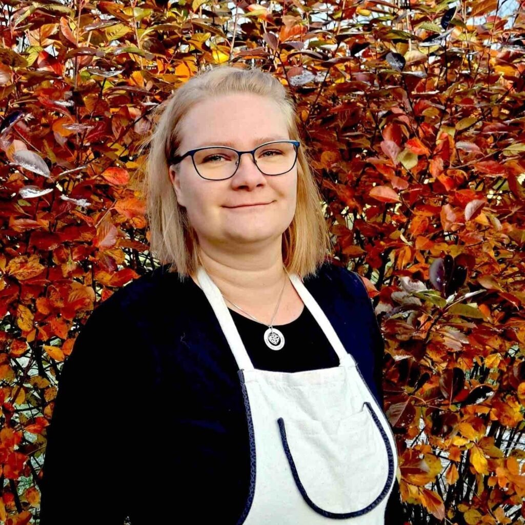 Mira, vaalea suomalainen nainen hymyilee esiliinassa, kotiapupalveluja edustava kuva